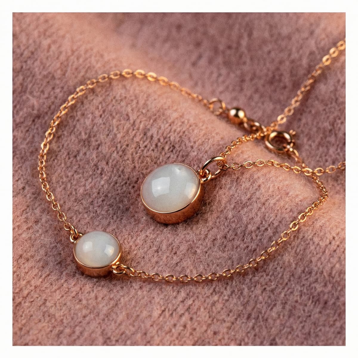 Rose-gold chain bracelet with two milky white breastmilk resin stone charms on a soft pink fabric background, a sentimental keepsake jewelry idea among the best push presents for new moms.