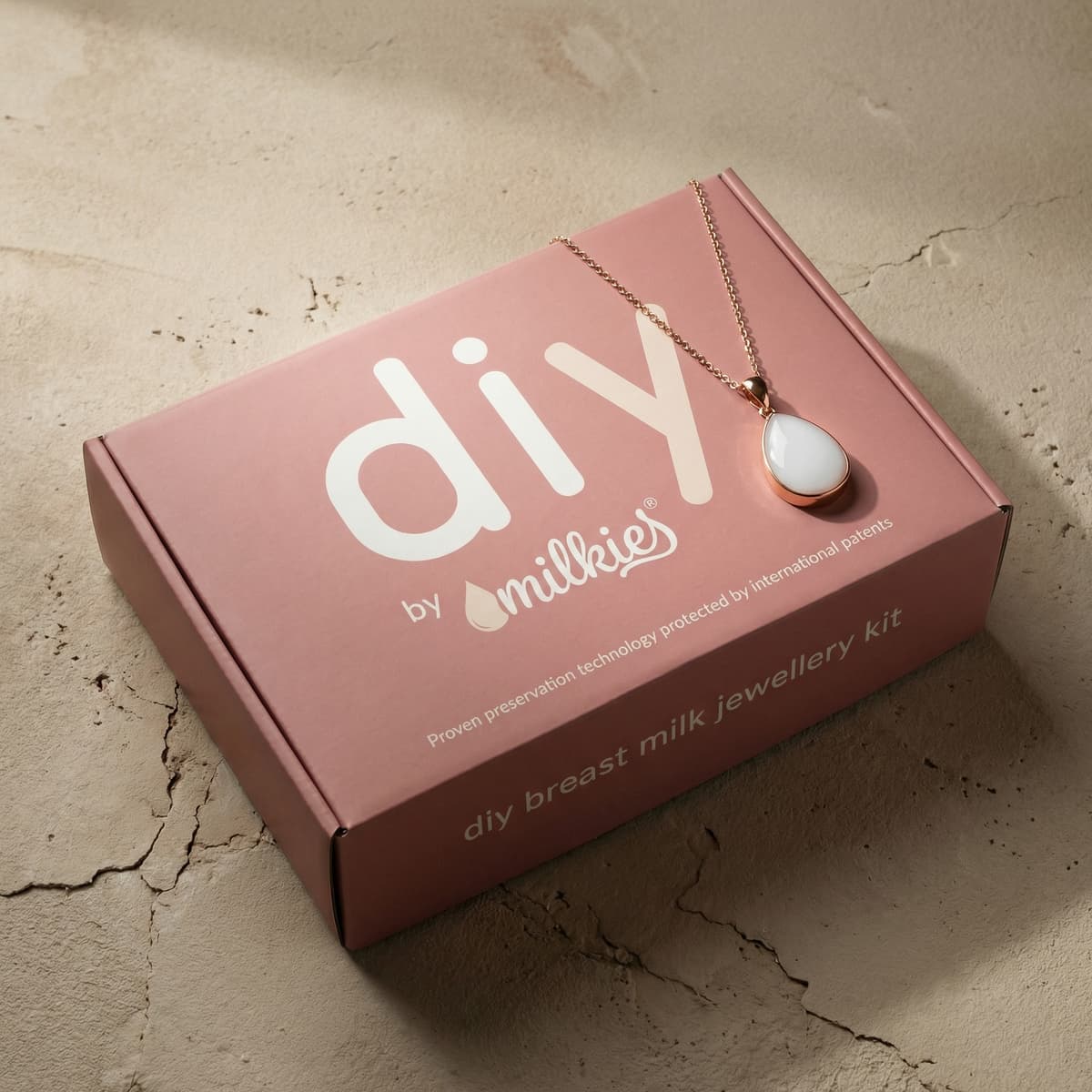 Pink DIY by MILKIES breast milk jewellery kit box featuring a rose-gold chain and white teardrop pendant, a thoughtful breastfeeding gift for moms to create a keepsake at home.