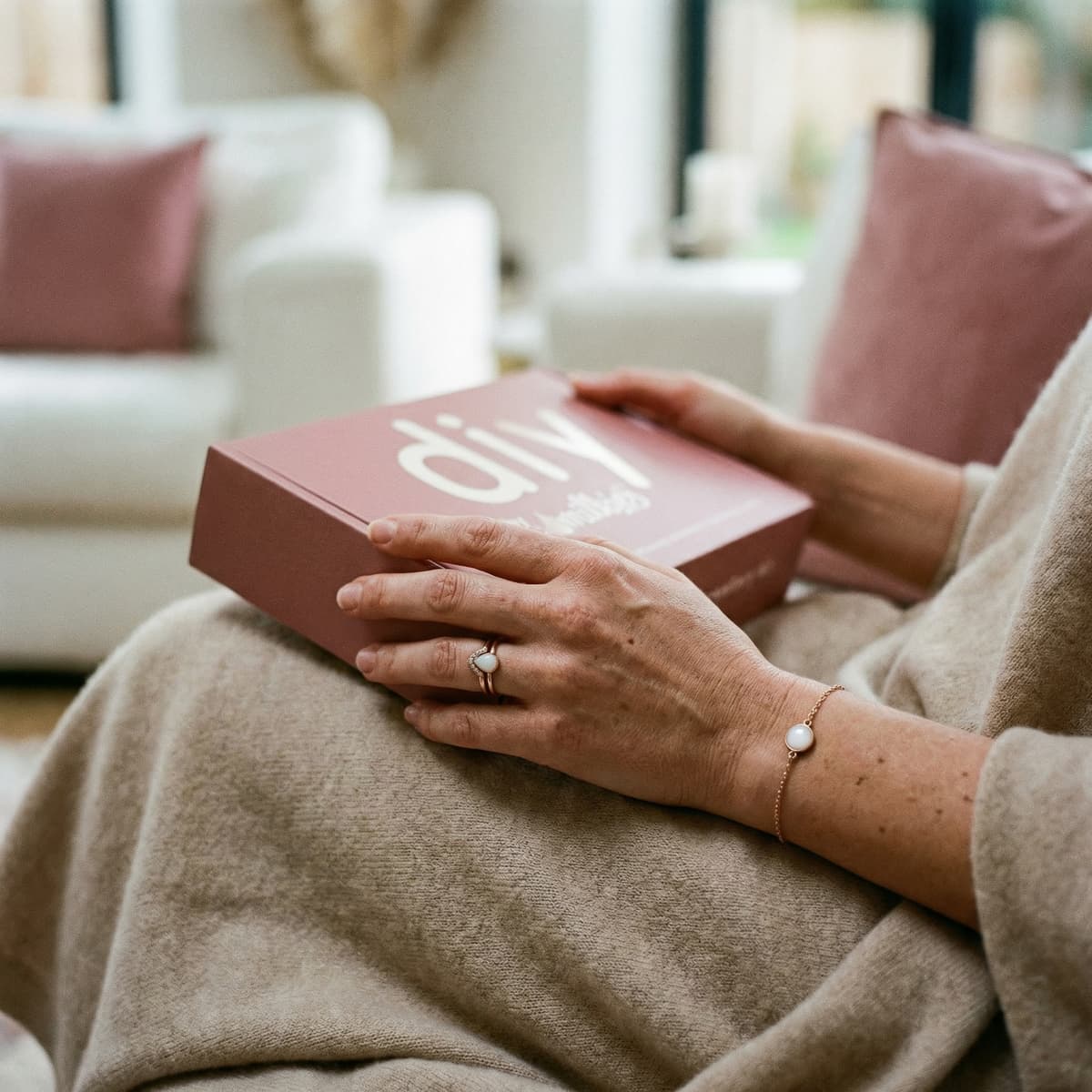 Woman at home holding a DIY by MILKIES box, showing why a breastmilk jewelry resin kit is a meaningful, private way to create a keepsake with professional-quality results.