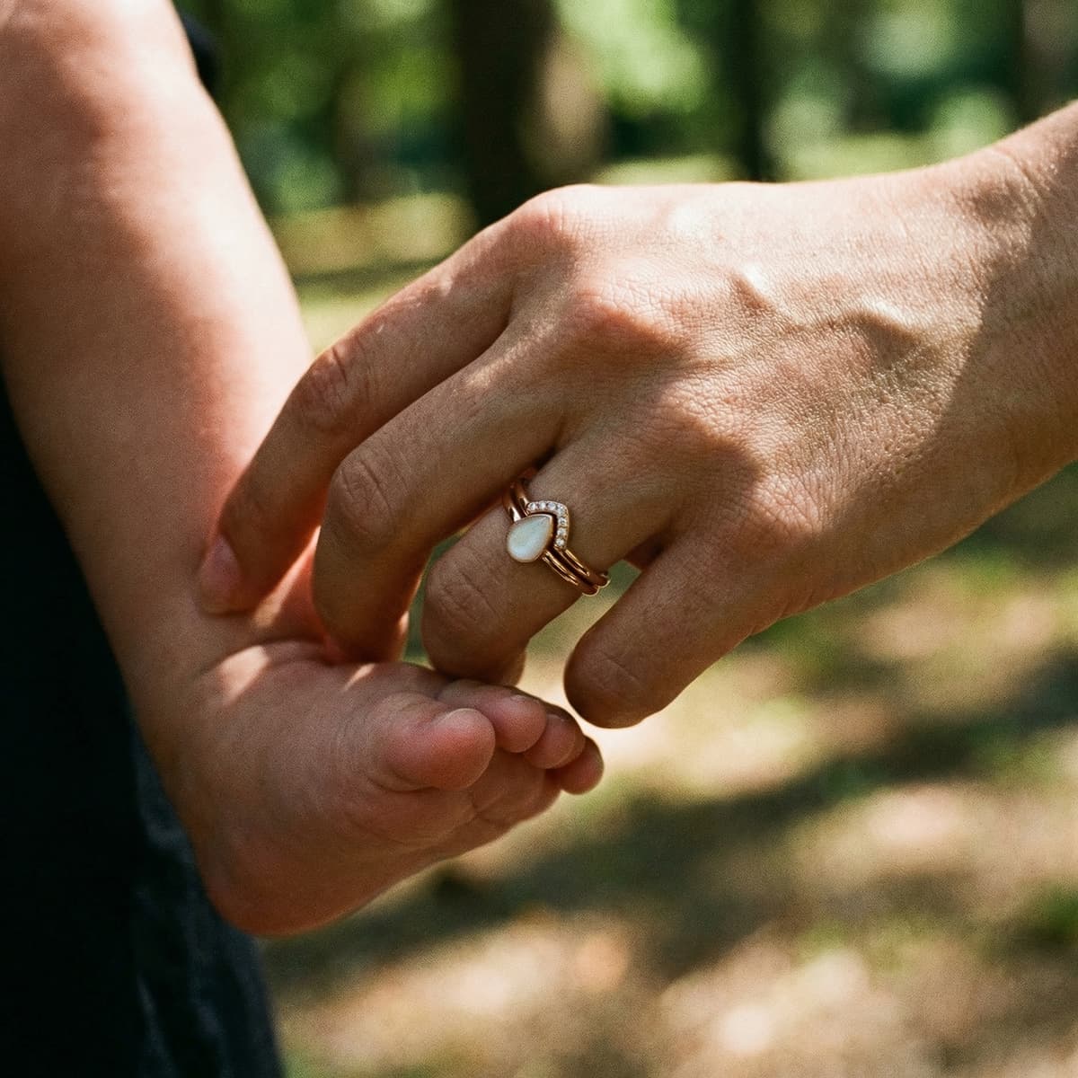 Mother holding a baby’s foot while wearing a rose-gold keepsake ring with a milky white stone, highlighting a breastmilk ring diy kit for memory jewelry making at home.