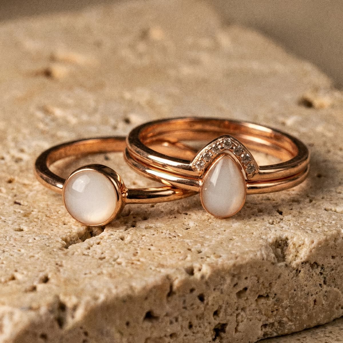 Rose gold breastmilk keepsake rings with milky white resin stones, finished using a breastmilk ring kit, displayed on a textured stone surface.