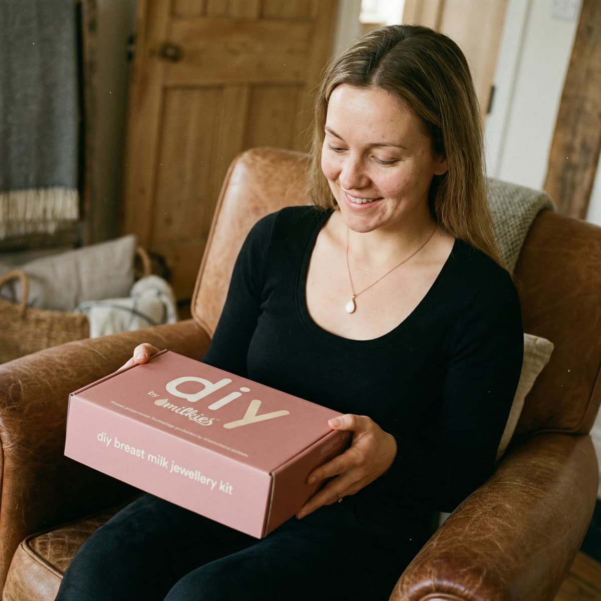 Smiling mom at home opening a DIY by MILKIES kit, showing why a diy breastmilk necklace is a meaningful, private way to create a keepsake yourself with an at-home breast milk jewelry kit.