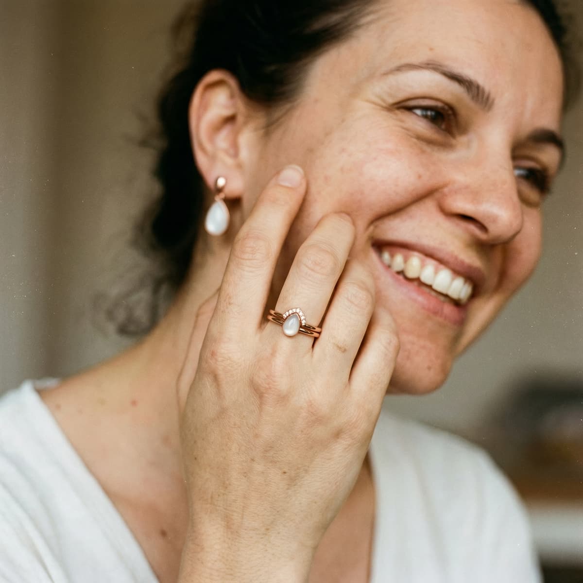 Smiling mother wearing a rose-gold keepsake ring with a milky-white stone, showing why a diy breastmilk ring kit is a meaningful at-home choice for preserving your motherhood journey.