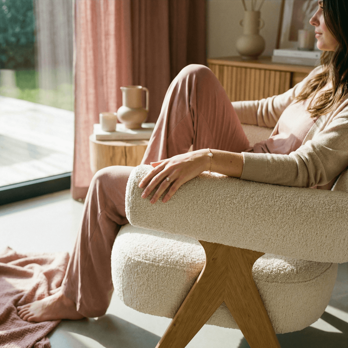 Mother relaxing in a cozy armchair beside a sunlit window, illustrating postpartum self-care and support while drying up milk