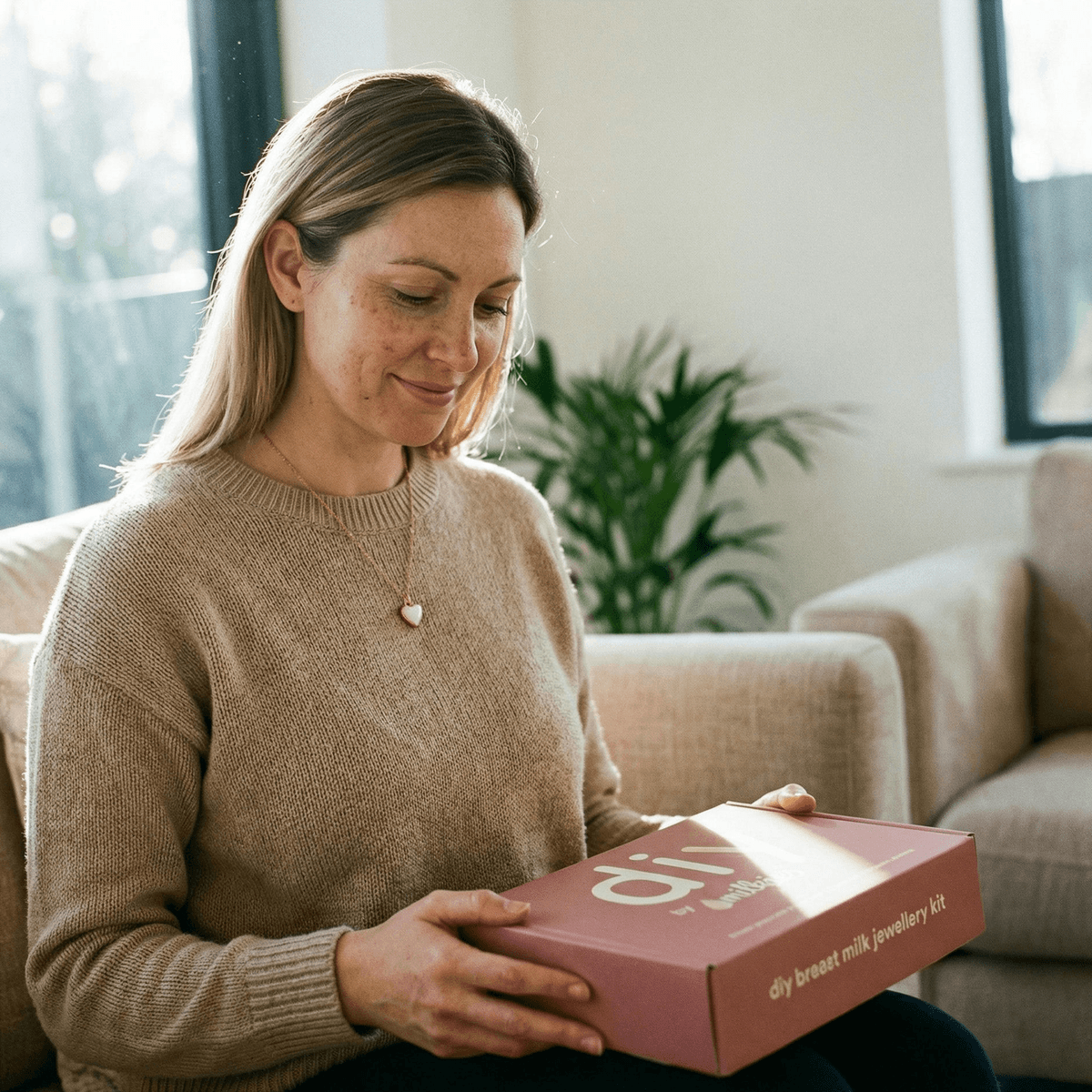 Mom holding DIY by MILKIES breast milk jewelry kit box, showing why an at-home kit is a good idea for creating a private, convenient last feed keepsake at home.