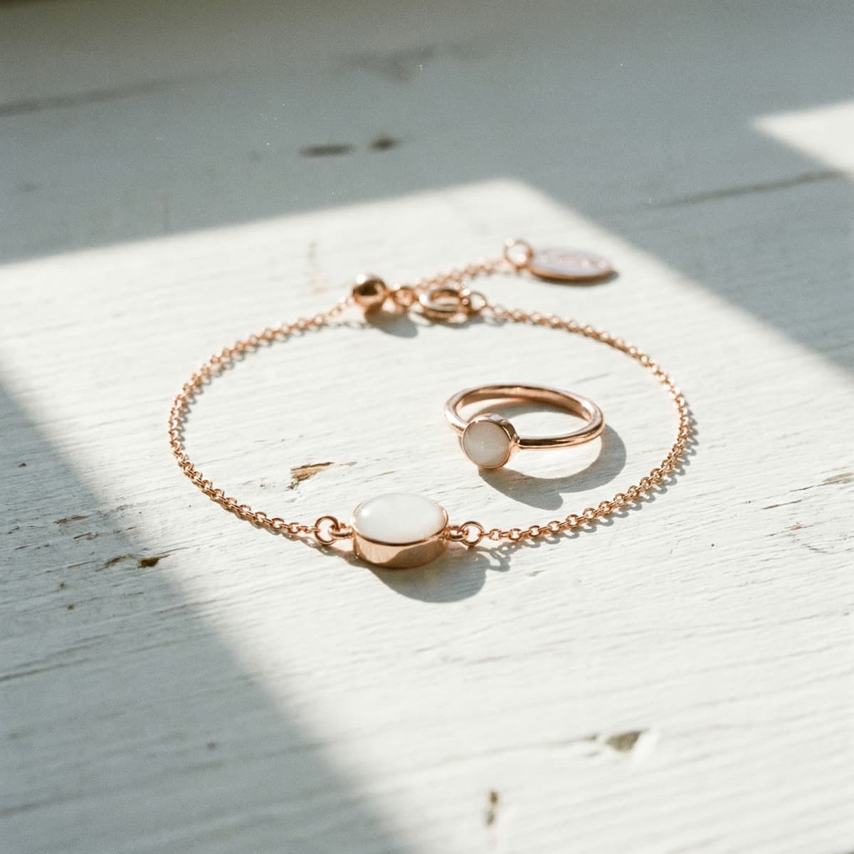 Rose gold bracelet and matching ring with milky white resin stones in soft sunlight, showcasing a breastmilk bracelet diy kit keepsake jewelry set.