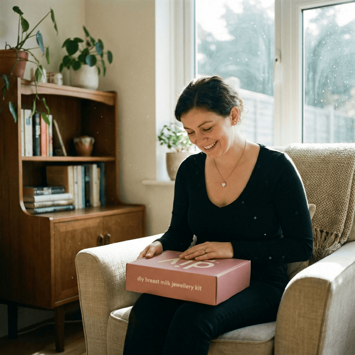 Smiling mom at home holding a DIY by MILKIES box, highlighting why a breastmilk jewelry diy making kit is a convenient, private way to create a personal keepsake at home.