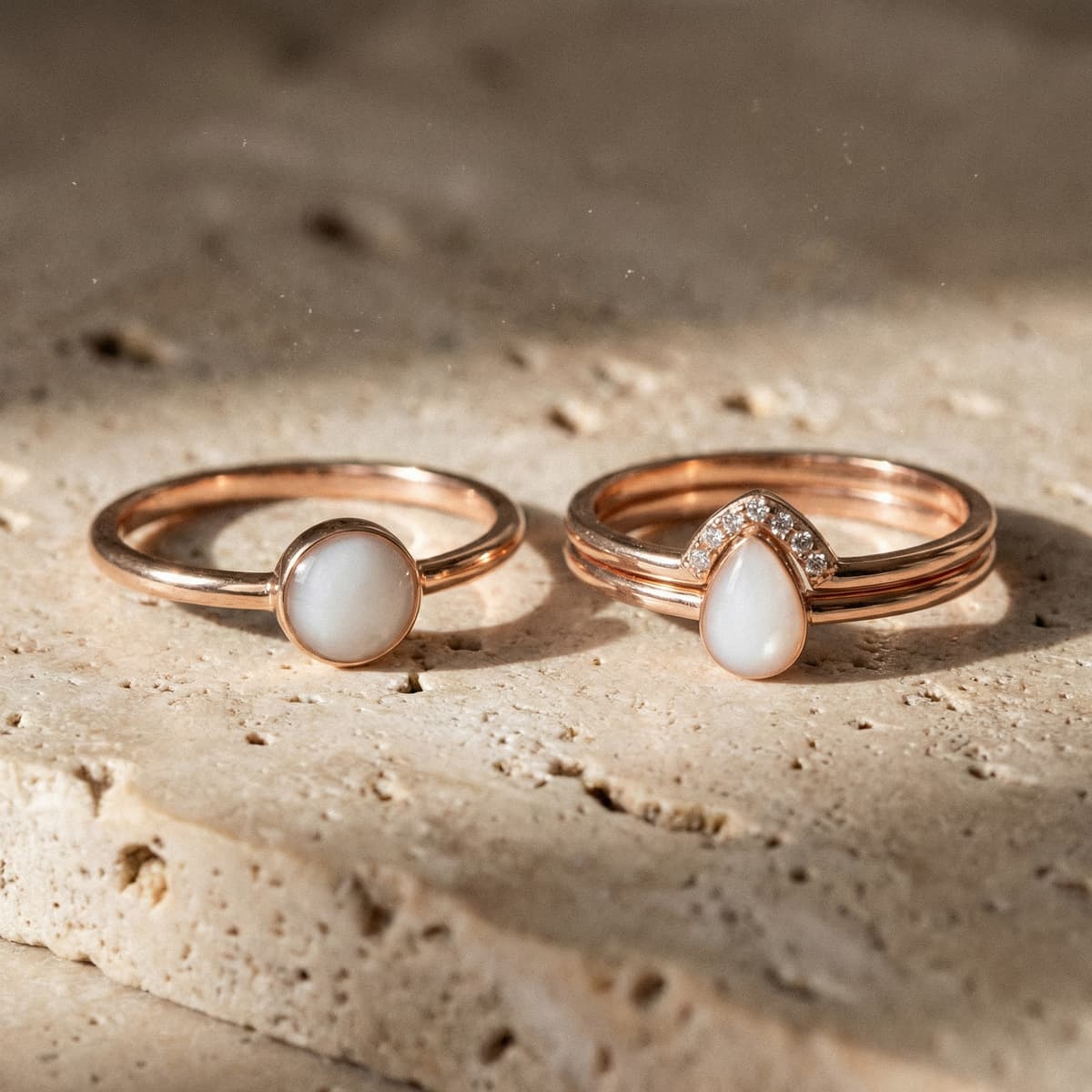 Two rose-gold keepsake rings with milky white resin stones made using a diy breastmilk ring making kit, displayed on a textured stone surface.