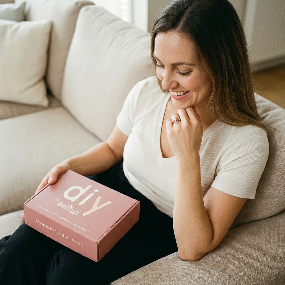 Smiling mother at home holding a DIY by MILKIES box, highlighting why choosing a diy breastmilk ring making kit is a convenient way to create a private, personal breastmilk jewellery keepsake.