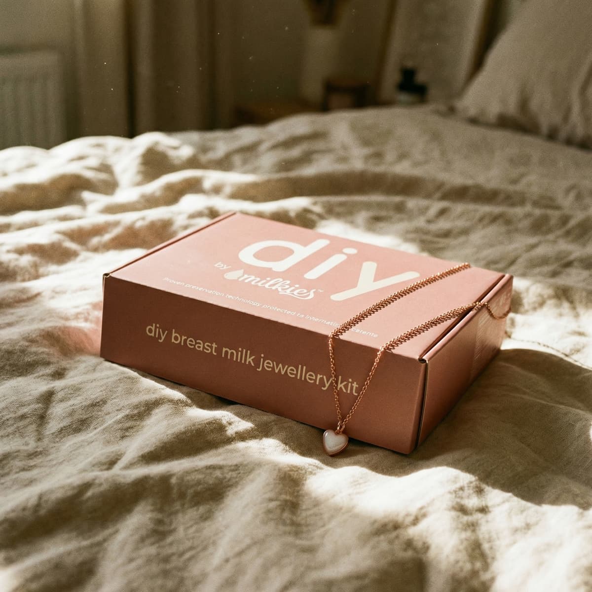 Warm bedroom scene with DIY by MILKIES breast milk jewellery kit box and heart pendant necklace, a meaningful gift for new mother’s day gift to create a keepsake at home.